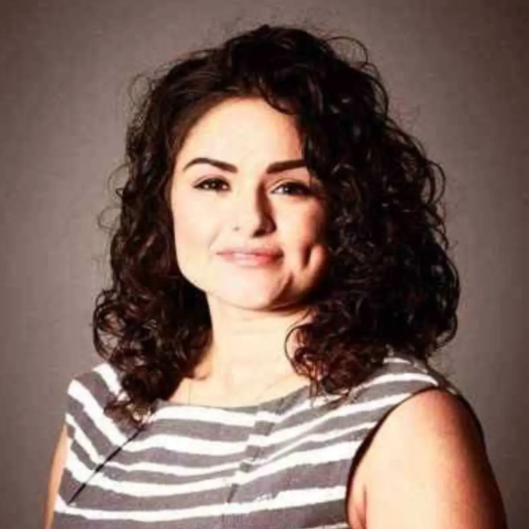 Woman with curly hair smiling in striped shirt.