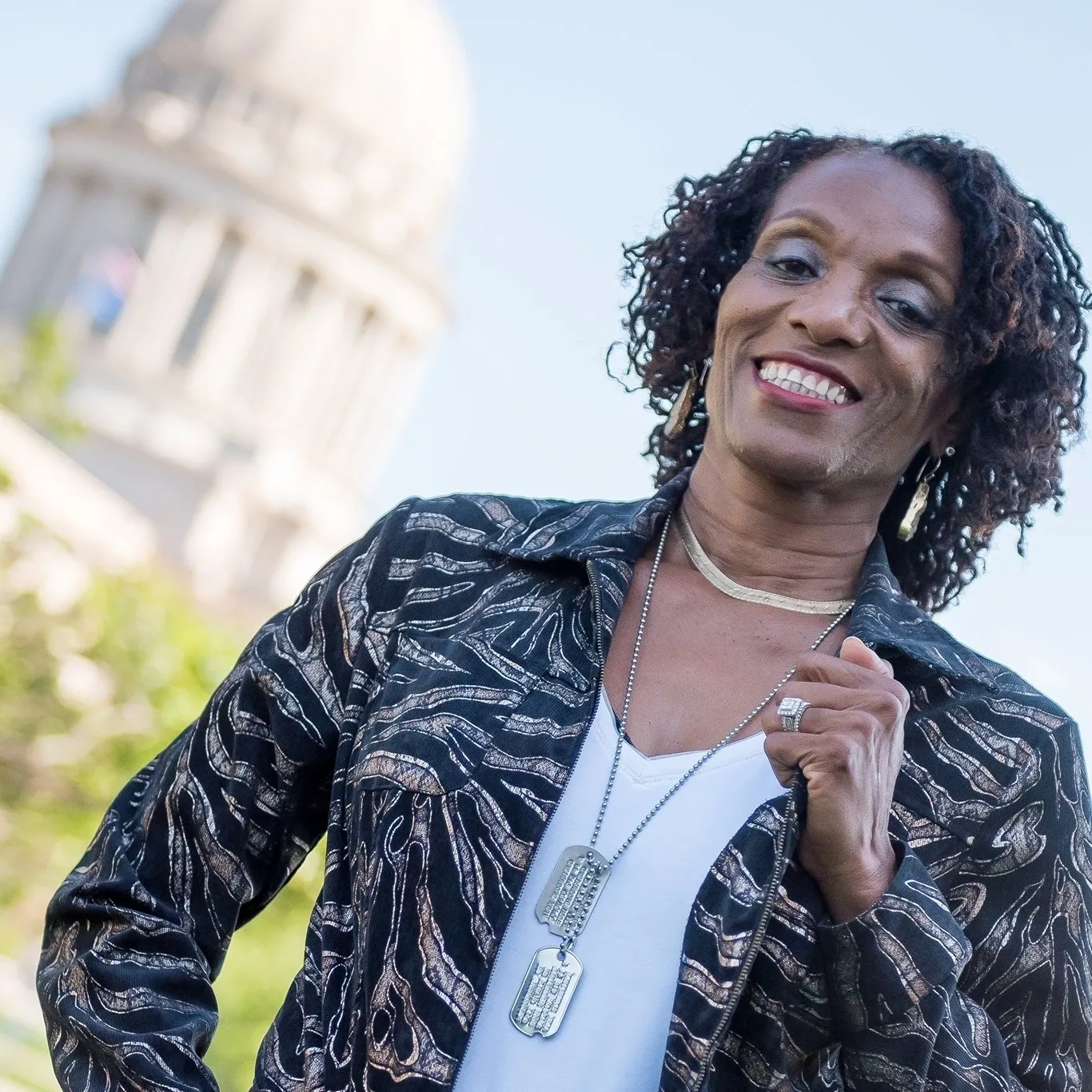 Smiling woman wearing a black jacket with dog tags.