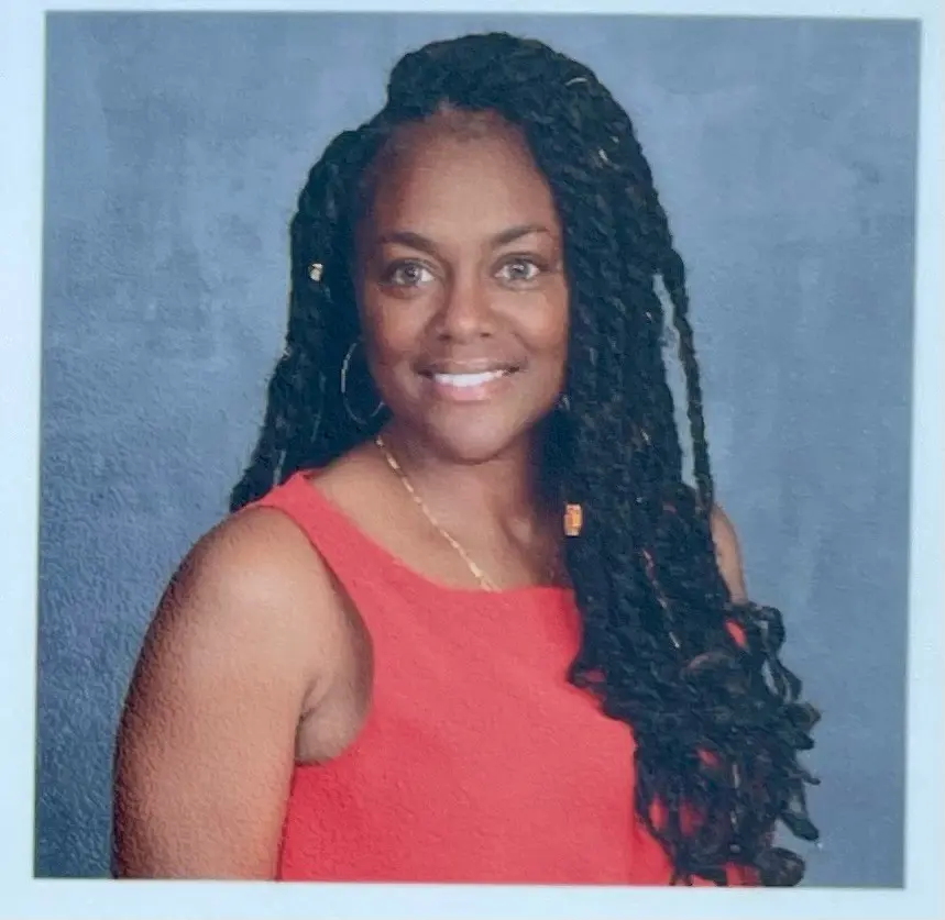 Woman with long braids wearing a red top.