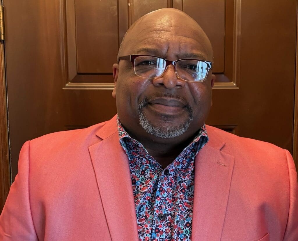 Man in a pink blazer and glasses.